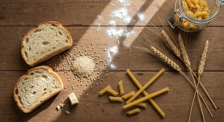 Bezlepkové potraviny na dřevěném stole: chléb, quinoa a těstoviny bez lepku