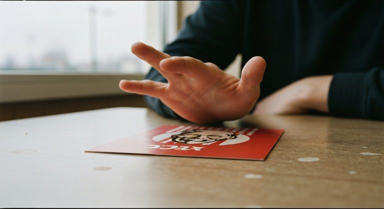 Ruka nad menu KFC na opotřebovaném stole, váhání před objednávkou
