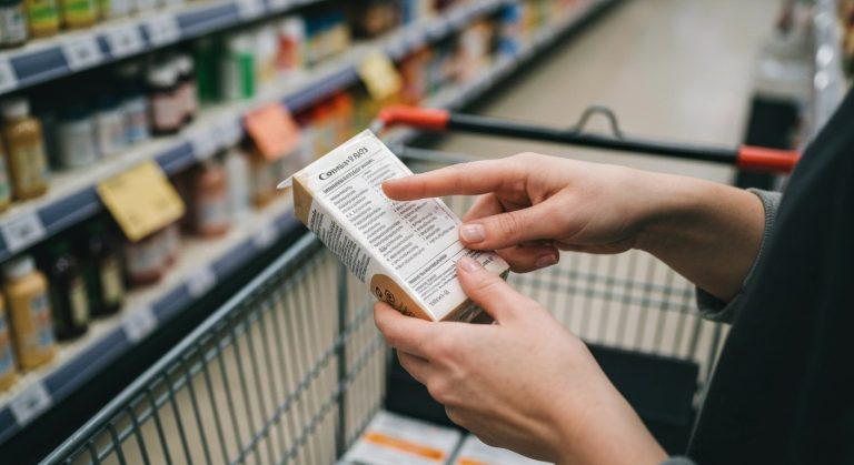 Ženské ruce drží potravinu a kontrolují složení na etiketě v obchodě