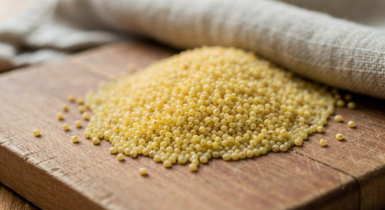 Detailní záběr syrových jáhel na dřevěném prkénku s lněným utěrkou